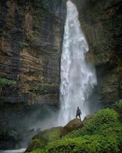 personne debout sur une formation rocheuse brune regardant les cascades pendant la journée
